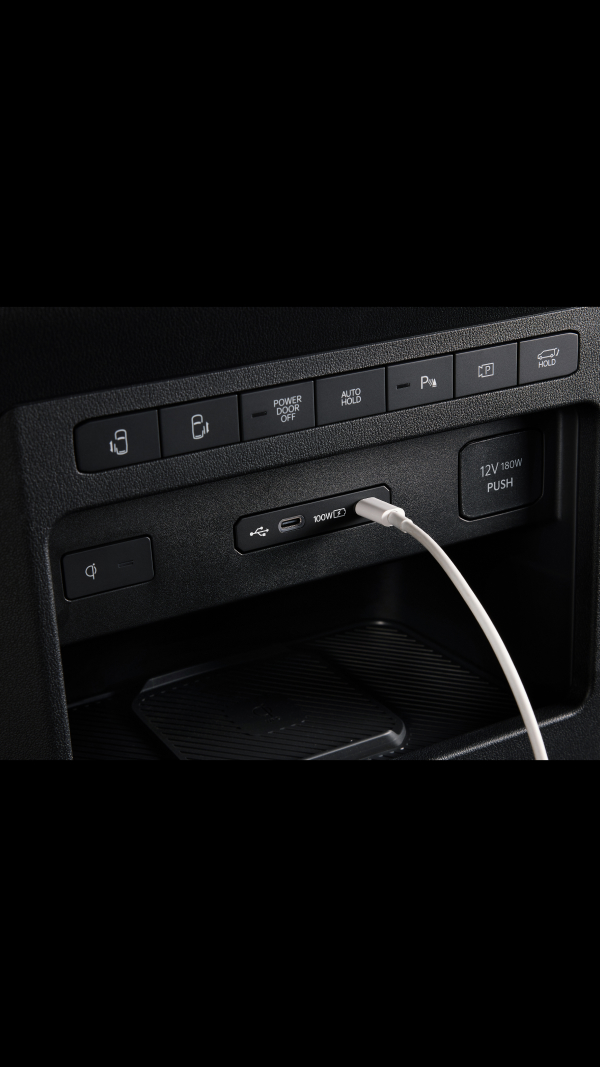 Nahaufnahme eines 100-W-USB-C-Anschlusses im Kia PV5 WAV beim Laden eines Geräts im vorderen Innenraum.