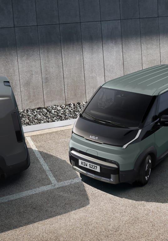 Kia PV5 WAV verlässt eine Parklücke – der aktive Totwinkelassistent erkennt sich von hinten nähernde Fahrzeuge.